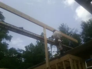 Carpenter setting a ridge beam over a new addition frame — Ice Dam Removal by Roofing Brothers in Volcano