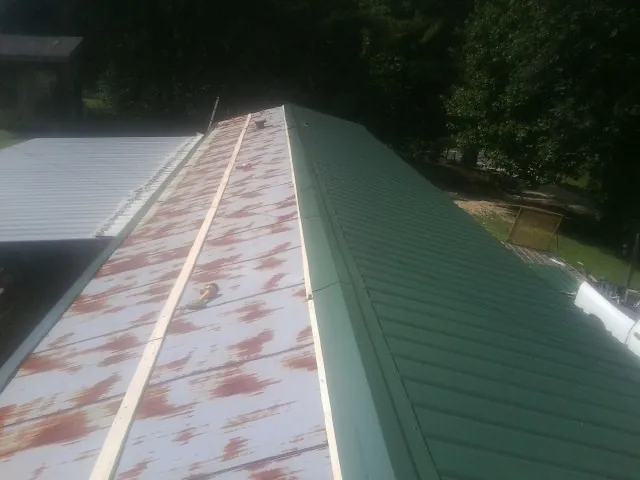 Old rusted panels beside newly installed green metal roofing — Wind Damage Roof Repair by Roofing Brothers in Volcano