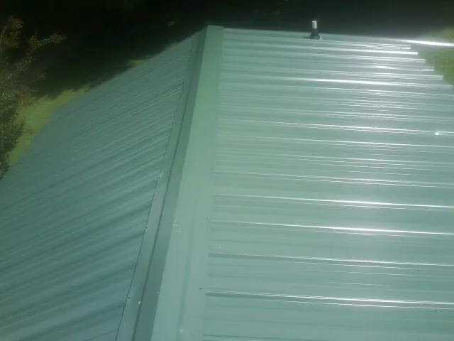 New green metal panels meeting at the ridge of a roof — Flat Roof Repair work by our crew in Volcano