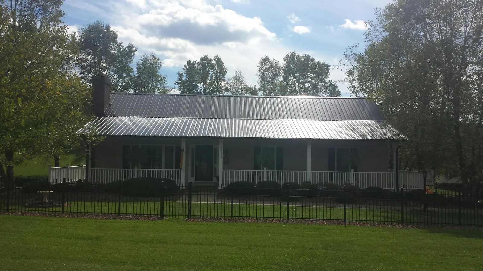 Gray metal roof on a brick ranch with a full width front porch — Gutter Guard Installation work by our crew in Volcano