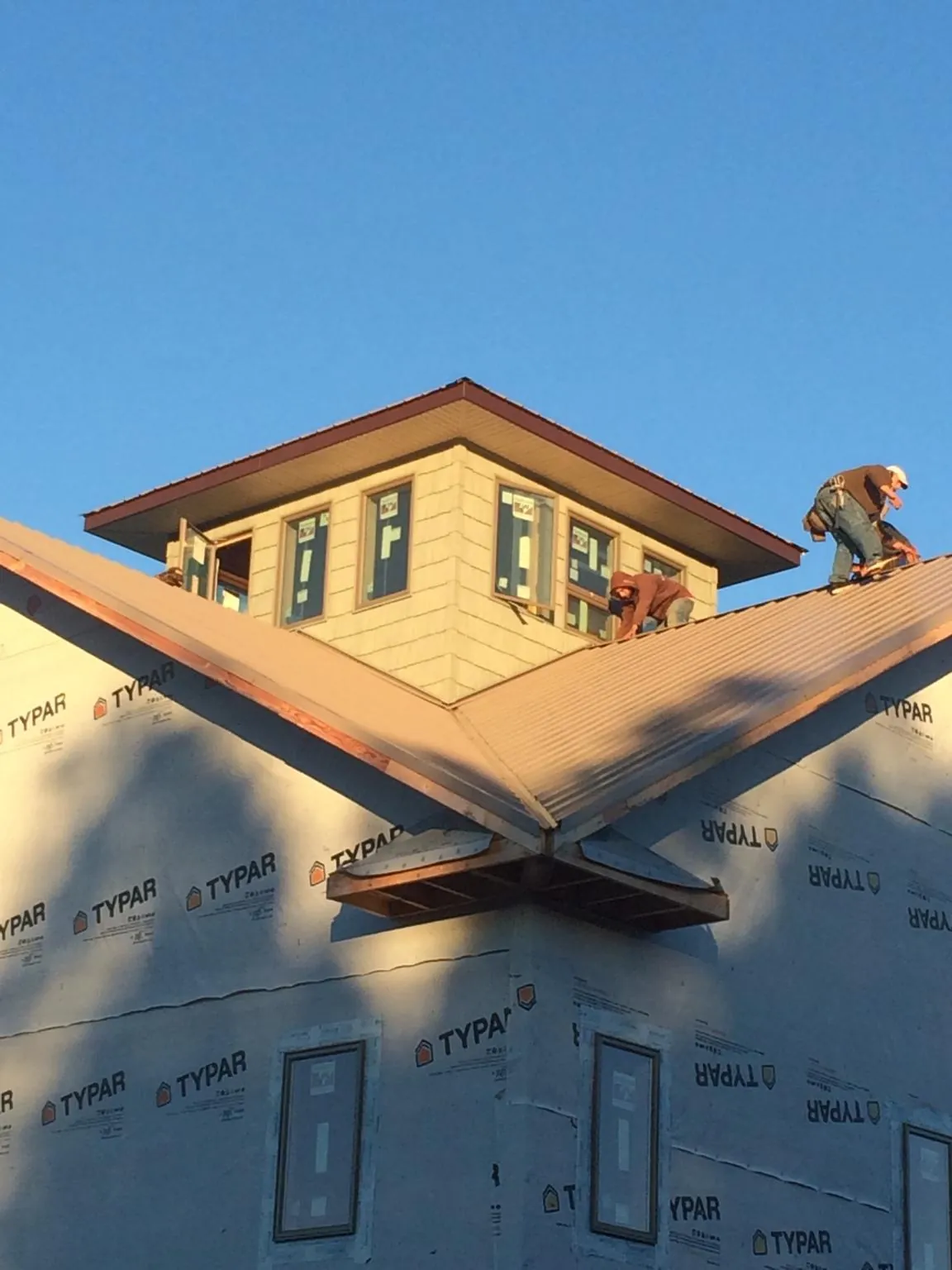 Roofers working around a rooftop cupola on a new metal roof at sunset — Roof Waterproofing in Volcano by Roofing Brothers